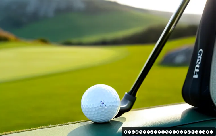 휴대용 골프 스피커 추천 - Photorealistic portable golf speaker resting beside a golf ball and club on a neatly trimmed fairway...